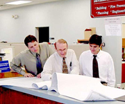 3 men looking over documents in an office