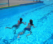 2 people swimming in a pool with bright blue water